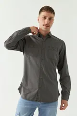 Camisa de gabardina gris con corte slim, mangas largas, cartera abotonada y dos bolsillos con solapa en el pecho.