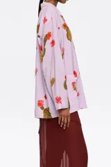 Camisa de viscosa color lila con estampado de cactus y flores rojas, corte recto, cuello con solapas, manga larga recta, cierre frontal con botones y bolsillos de plastrón.