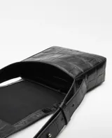 Bandolera pequeña de piel bovina negra con grabado de cocodrilo. Presenta solapa con cierre magnético, asa larga regulable y bolsillo interior con cierre.