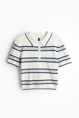 Remera polo de punto fino color blanco con rayas horizontales celestes y azul marino. Tiene cuello clásico, tapeta con botones y mangas cortas.