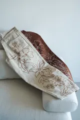 Pantalón slouchy tiro medio color beige con bordado floral marrón.