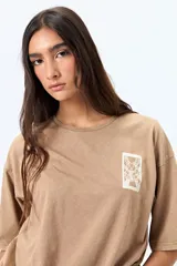 Remera negra de corte amplio con mangas cortas y cuello redondo. Presenta un pequeño estampado rectangular en el pecho y un estampado grande en la espalda con motivos japoneses.