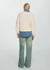 Sweater color crema de tejido de punto grueso con cuello redondo y manga larga. Presenta terminaciones de canalé y bordado de perlas en la parte delantera.