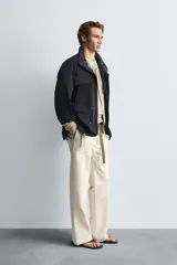 Parka azul marino de tejido técnico, corte relaxed fit, cuello alto ajustable con cordón, manga larga con puños abotonados, cierre frontal con cremallera oculta y solapa con botones a presión, cintura ajustable con cordón interior y bolsillos frontales multifunción de plastrón.
