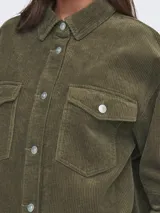 Camisa verde militar de pana con corte oversize, cuello clásico, cierre frontal con botones, mangas largas con puños abotonados, bolsillos de parche en el pecho y forro de jersey de algodón.