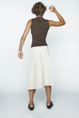 Falda midi color crema, de corte asimétrico y diseño cruzado con lazos laterales.