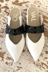 Slippers de cuero blanco con detallado de faja de charol negro con tachas, tacón bajo de 2 cm.