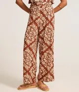 Pantalón pantalona con cintura alta, cintura ancha con botones forrados en los laterales y estampa tropical estilo pañuelo con flores.