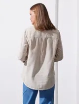Camisa color beige de lino, marca Dash. Tiene cuello con solapa, abertura central con botones, bolsillo aplicado en el pecho y mangas largas regulables con presilla y botón.