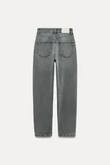 Pantalón de jean gris oscuro, de corte mom fit, tiro alto y largo tobillero. Cuenta con cinco bolsillos, cierre frontal con cremallera y botón.