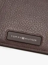 Billetera plegable de cuero texturizado color marrón, con múltiples ranuras interiores para tarjetas, compartimento para billetes, bolsillo para monedas y logo metalizado de Tommy Hilfiger en la parte delantera.