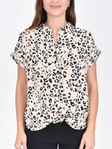 Camisa de manga corta con estampado animal print en tonos beige, marrón y negro. Tiene cuello mao y cierre frontal con botones.