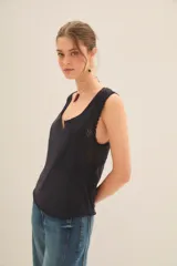 Musculosa de tejido de punto color beige claro, con escote en V profundo y sisas con detalle de encaje calado en patrón de espiga.