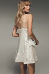 Vestido corto de fiesta color blanco, con lentejuelas y volantes.