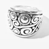 Anillo plateado con diseño de espirales y círculos.