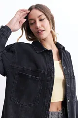 Campera de jean celeste de corte holgado, con cuello camisero, cierre frontal con botones metálicos, mangas largas con puños abotonados, bolsillos frontales con solapa y costuras a la vista.