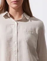 Camisa color beige de lino, marca Dash. Tiene cuello con solapa, abertura central con botones, bolsillo aplicado en el pecho y mangas largas regulables con presilla y botón.