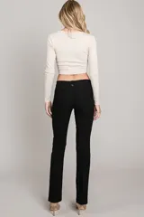 Pantalón negro de corte recto, tiro bajo y pierna angosta.
