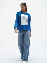 Blusa azul con estampado abstracto en blanco y negro, de mangas largas.