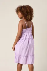 Vestido corto lila con breteles finos, escote en V con botones y falda escalonada con volados.