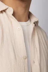 Camisa de lino blanca de manga larga, con cuello clásico y cierre frontal con botones. Corte recto y holgado.