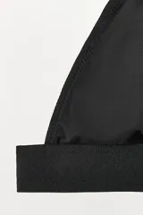 Bralette negro de viscosa con escote en pico, tirantes finos ajustables, cierre trasero con gancho y pieza metálica decorativa en el pecho.