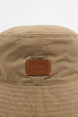 Gorro tipo bucket color marrón de gabardina con etiqueta de cuero con logo de la marca.