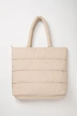 Bolso tipo tote bag color beige, con diseño acolchado horizontal y doble asa de hombro.