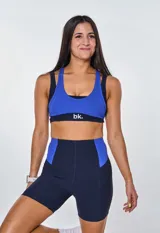 Conjunto deportivo de calza corta y top con logo 'bk.' estampado. El top es de color azul con base negra y la calza es de color azul marino con paneles laterales azules.