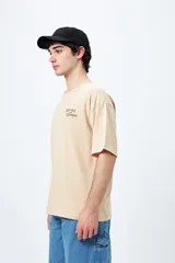 Remera blanca de corte holgado con mangas cortas y cuello redondo. Estampado pequeño en el frente con la frase "Spritz and Shine" en verde.
