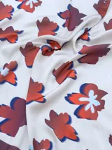 Pañuelo cuadrado de seda color crema con estampado de flores rojas, azules y blancas. Tiene borde marrón.