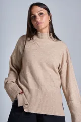 Sweater color crema de media polera, corte holgado y mangas largas. Tejido de punto con detalles acanalados en cuello, puños y ruedo.