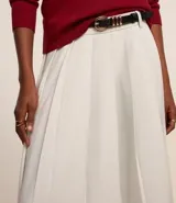 Pollera midi de poliéster color blanco, de sastrería, con pliegues y trabillas en la cintura.