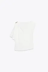 Top blanco de satén con cuello amplio y manga asimétrica con detalle de fornitura dorada en el hombro.