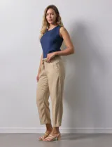 Pantalón color beige, marca Dash, de corte cropped y pretina trasera elastizada. Presenta bolsillos delanteros y traseros.