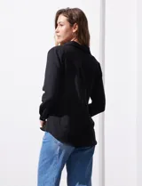 Camisa blanca de manga larga con cuello con solapa y abertura central con botones. Delantera con bolsillos aplicados.