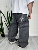 Pantalón baggy de denim gris con efecto lavado y estampado de cruz abstracta en los bolsillos traseros.
