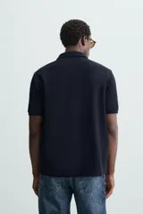 Polo de piqué color crudo, corte regular fit, cuello solapa con cierre de botonadura y mangas cortas.