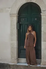 Chaleco top marrón con cuello halter, detalle de nudo y cierre frontal con botones.