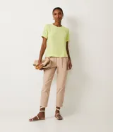 Blusa blanca de poliéster con cuello redondo, mangas cortas, cierre trasero en forma de gota, pequeñas aberturas laterales y acabados en pespuntes en las mangas y el cuello.