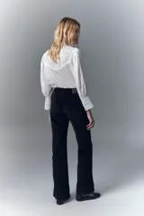 Pantalón de jean negro de pana, de tiro medio, ajustado en la cintura y con pierna levemente acampanada.