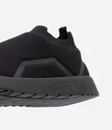 Championes negros de tela tejida, estilo slip-on, con suela blanca y detalles geométricos en los laterales.