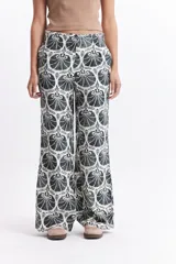 Pantalón wide leg estampado con diseño de conchas marinas color marrón sobre fondo blanco.