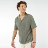 Camisa verde de manga corta con tejido calado, cuello clásico y bolsillo en el pecho.