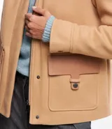 Saco color beige en polyvelour, con cuello alto, mangas largas, sisas desplazadas, cierre delantero y bolsillos con detalle en PU.