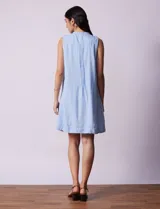 Vestido blanco de algodón y rayón, marca Dash. Cuello a la base, sin mangas y abertura central con botones. Delantera con detalle plisado y laterales con bolsillos.
