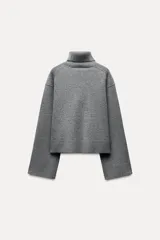 Sweater gris de lana con cuello alto, corte oversize y mangas largas acampanadas.