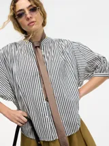 Camisa celeste a rayas verticales con botones en la parte delantera, cuello mao y mangas amplias.