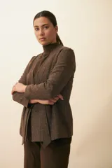 Chaqueta corta color beige, entallada, con escote en V, manga larga y cierre frontal con lazo fijo. Confeccionada en lana fina sin teñir, con bolsillos escondidos y terminaciones enviadas. Hecha 100% en Uruguay.