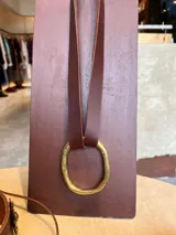 Gargantilla de cuero marrón con aro grande de bronce.